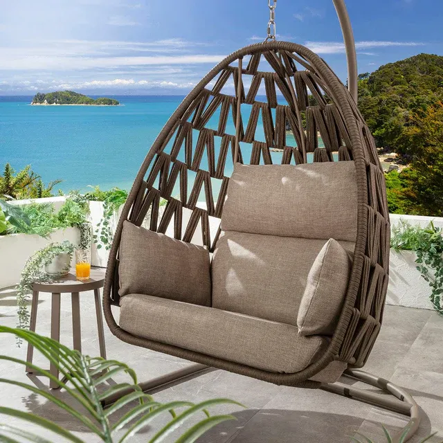 Brown rope hanging egg chair with neutral cushions